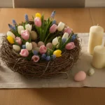 Table de Pâques élégante avec centre de fleurs printanières, oeufs pastel en osier et bougies ivoire sur nappe en lin