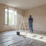 Salon en cours de rénovation avec bâche de protection au sol et artisan au travail