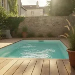 Mini piscine rectangulaire enterrée dans un petit jardin de ville, plage en bois et graminées en pot